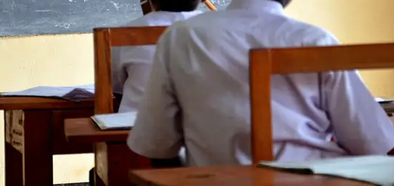 Students in white uniforms at wooden desks in a Tanzanian classroom